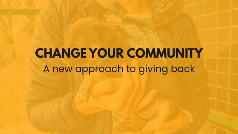 Text that says "change your community: a new approach to giving back" is displayed over a mostly transparent picture of a person holding a puppy at an animal rescue